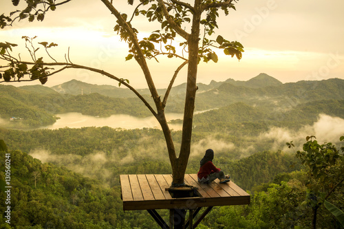 Woman sitting on observation point and looking at view photo