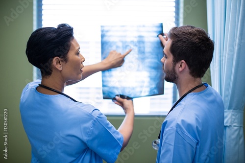 Male and female nurse discussing x-ray in ward