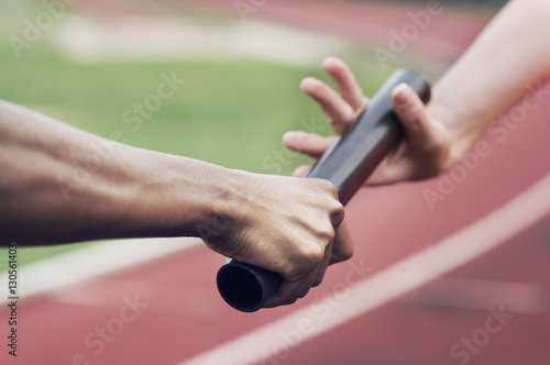 Cropped image of runner passing baton to teammate
