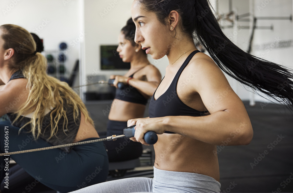 Female athletes exercising on rowing machines in gym Female athletes exercising on rowing machines in gym