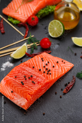 Fresh red fish (salmon fillet) and tomatoes, lime and chili pepper are ready for cooking.