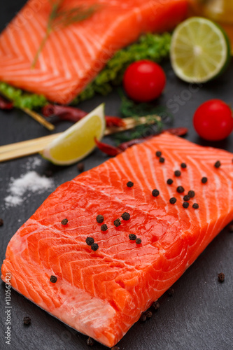 Fresh red fish (salmon fillet) and tomatoes, lime and chili pepper are ready for cooking.