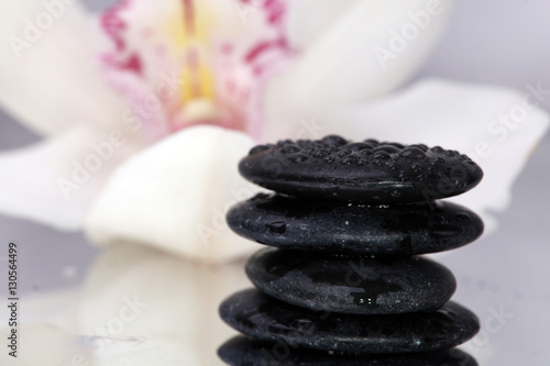 Spa background. Volcanic rock and orchids on reflective background with raindrops. Relaxation  body care treatment  spa  wellness concept