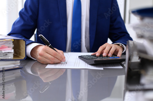 Close up view of bookkeeper or financial inspector hands making report, calculating or checking balance. Internal Revenue Service inspector checking financial document.