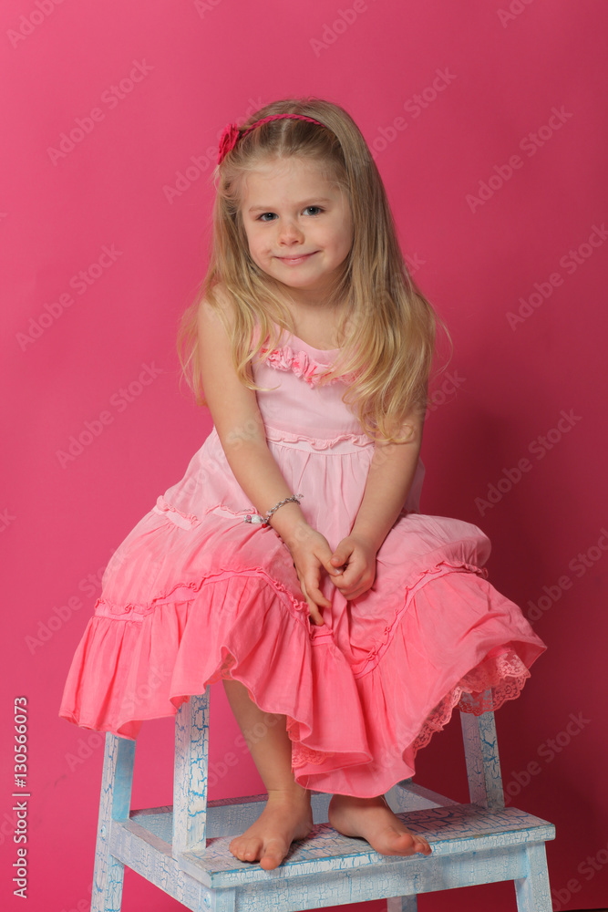 Sitting lady posing on chair. Pink background