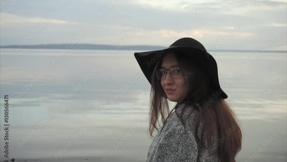 Young woman in black hat and glasses near the sea at sunset HD Young woman in black hat and glasses near the sea at sunset HD