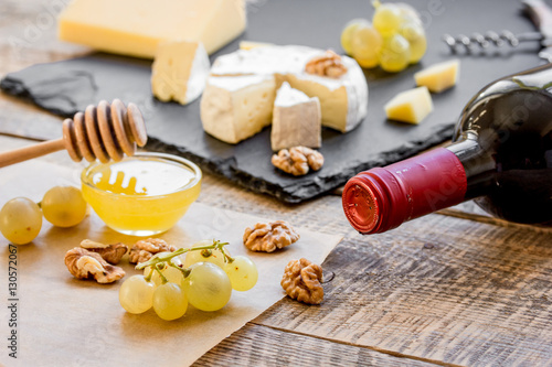 bottle of red wine, appetizers and corkscrew on wooden background
