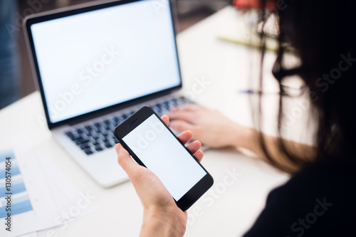 Close Up of woman hands using mobile phone and laptop computer with blank copy space screen for your advertising text message or content business.