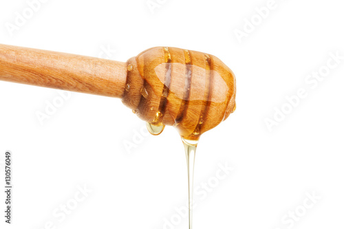 Honey dripping from wooden dipper stick. Isolated on white background with clipping path