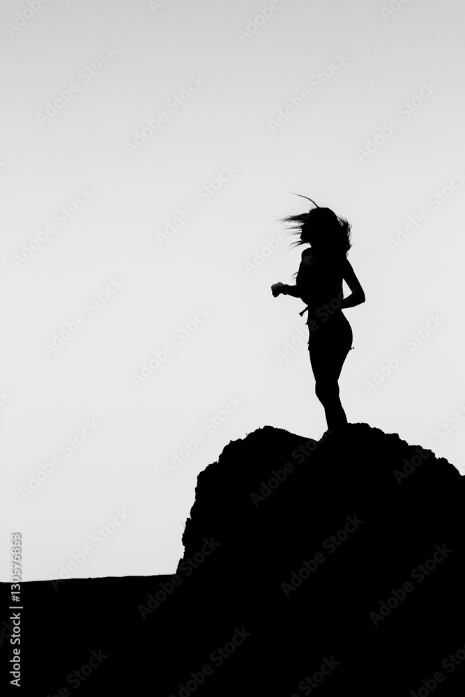 Silhouette of a girl on top of a mountain. 