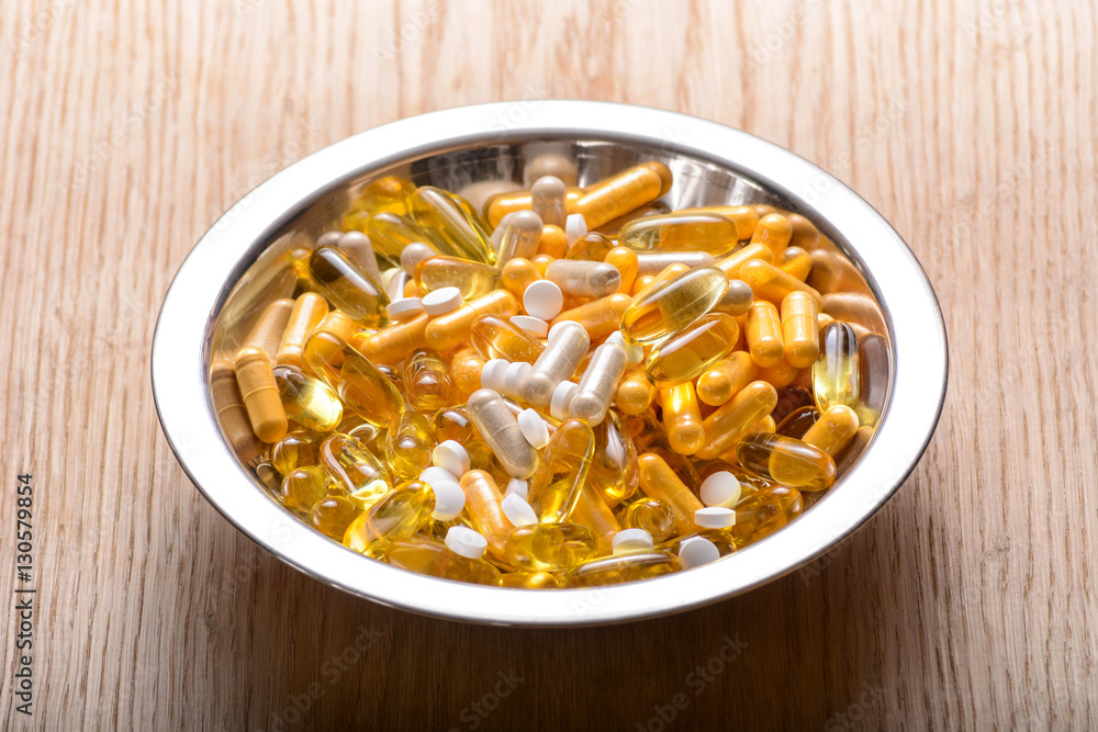 Fish oil capsules with omega 3 and vitamin supplements on a wooden texture, healthy diet concept Fish oil capsules with omega 3 and vitamin supplements on a wooden texture, healthy diet concept