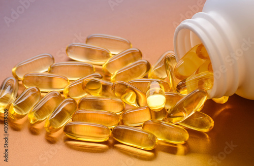 Fish oil capsules with omega 3 and vitamin D in a plastic bottle on a shiny texture, healthy diet concept
