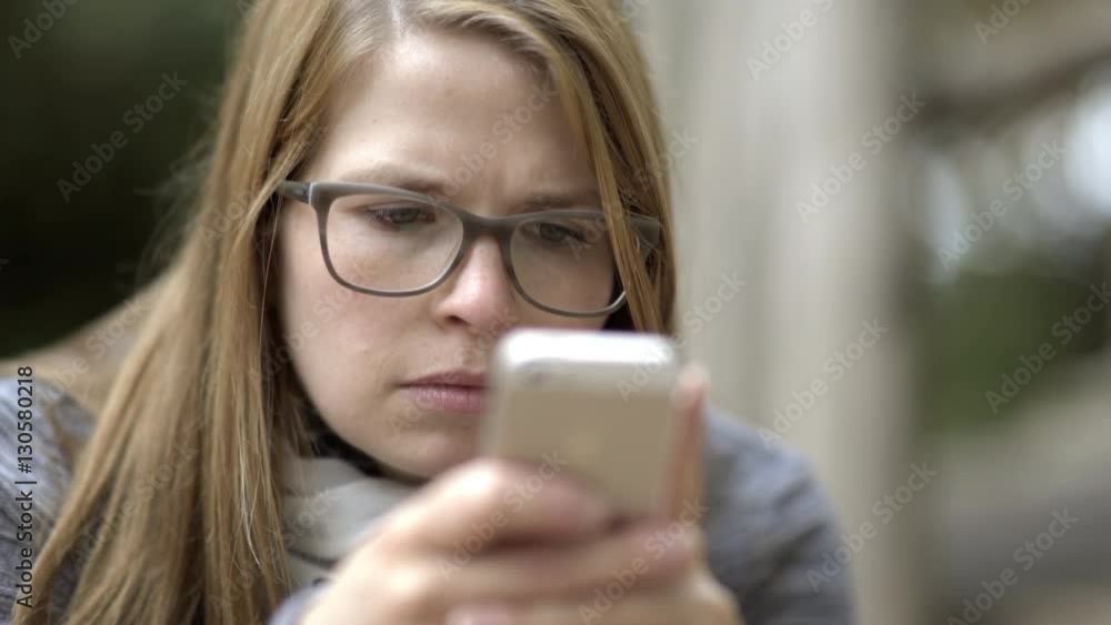 Female using her cell phone looks worried at the screen.
Female using her cell phone looks worried at the screen.