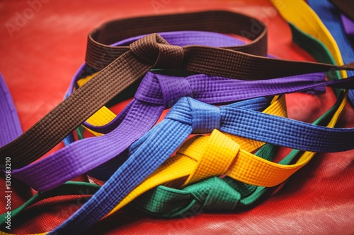 Multicoloured karate belts on red background photo