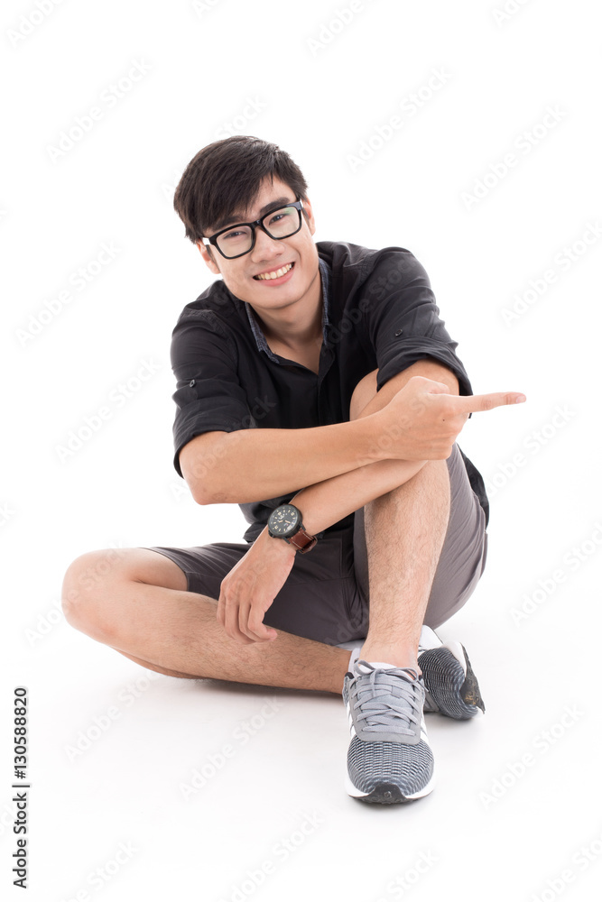 Naklejka premium Young man sitting on the floor, pointing and looking to his side