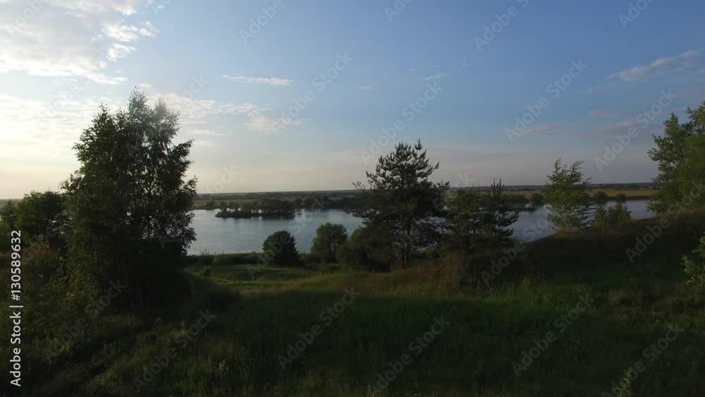 Flying over the trees offer a beautiful view of the river. Summer evening time. Calm water. Konstantinovo, the birthplace of great Russian poet Sergei Yesenin. Flying over the trees offer a beautiful view of the river. Summer evening time. Calm water. Konstantinovo, the birthplace of great Russian poet Sergei Yesenin.