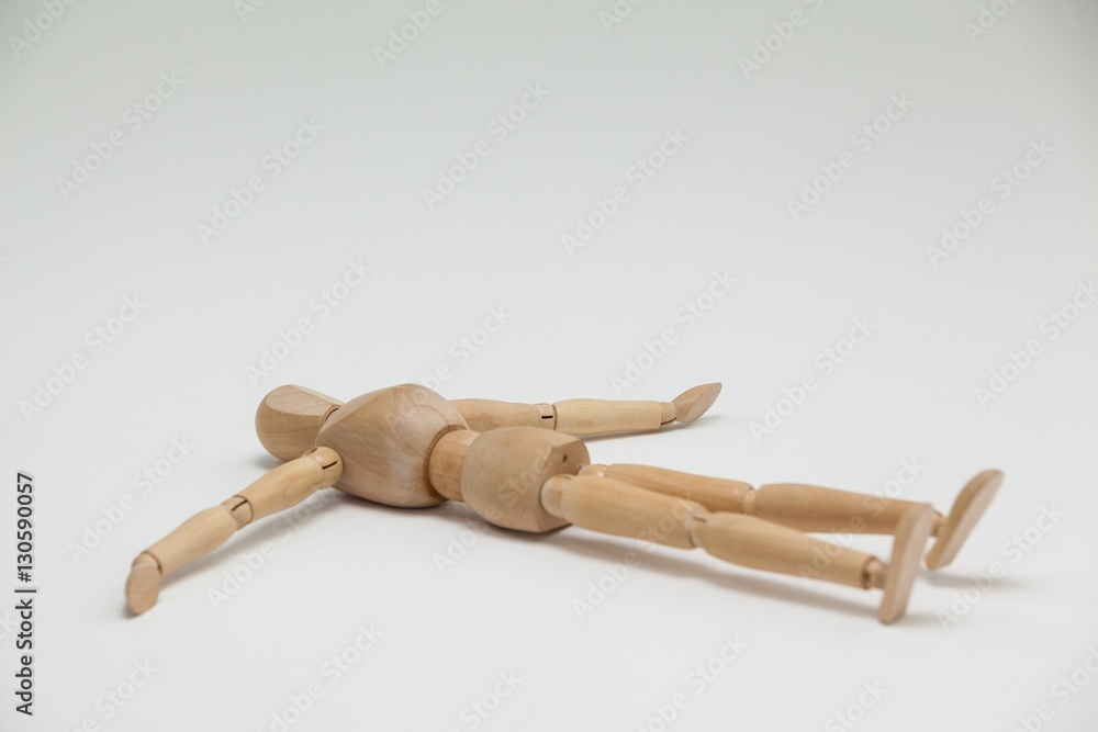 Wooden figurine lying on floor with arms spread Wooden figurine lying on floor with arms spread