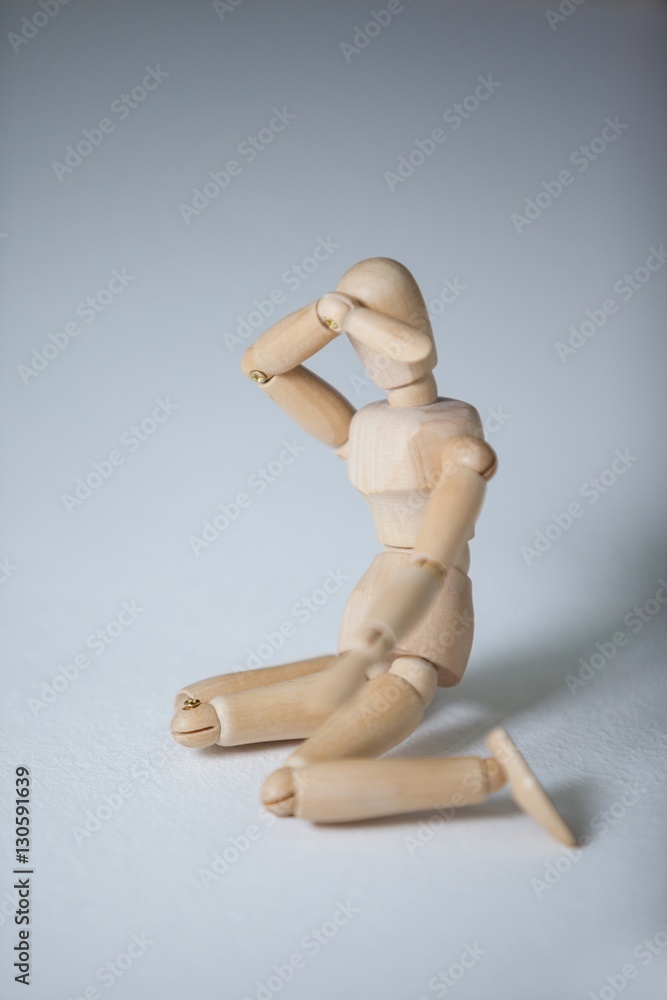 Wooden figurine sitting with hand on head Wooden figurine sitting with hand on head