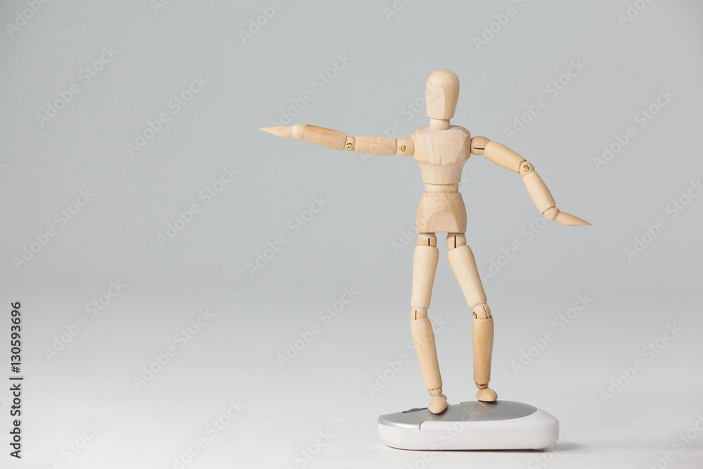 Wooden figurine standing with arms spread on a mouse Wooden figurine standing with arms spread on a mouse