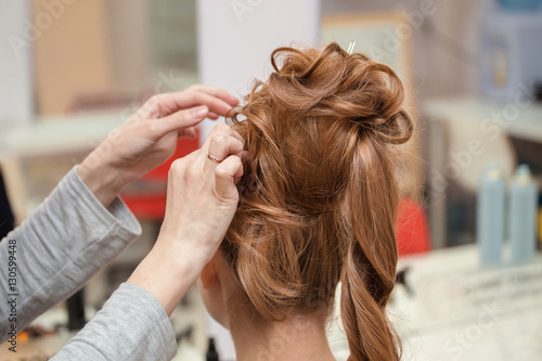 High Hairstyle creating process in hairdresser salon with elegant bun. Blonde and red hairs