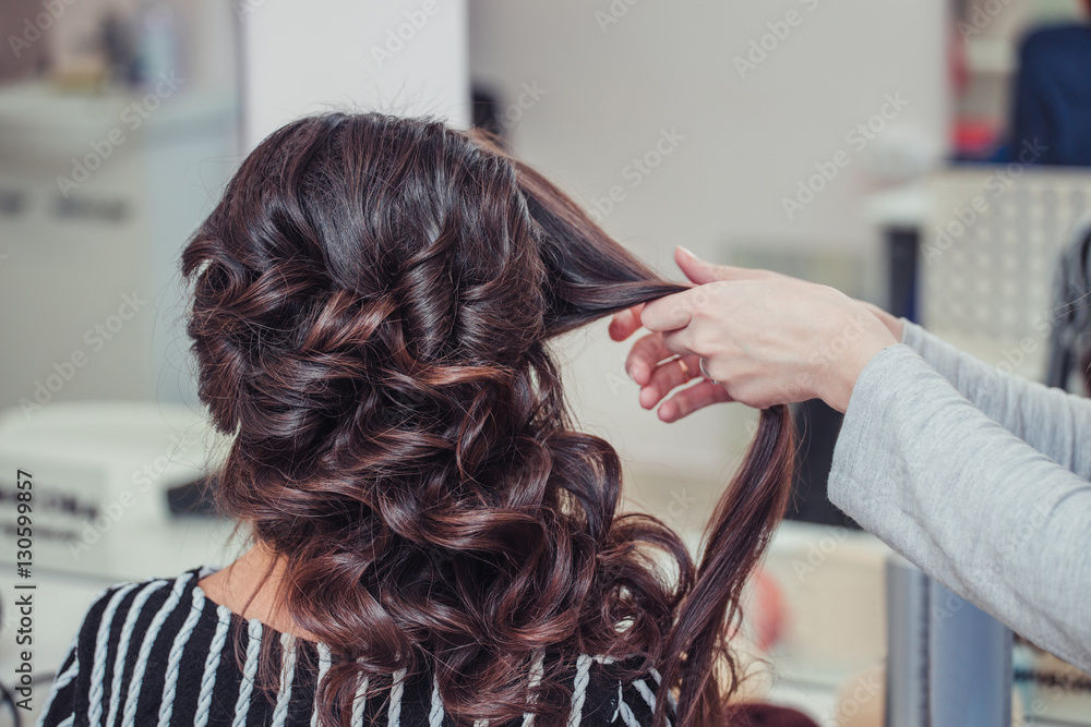Stylist curling hair and making wedding hairstyle for brown haired woman. Stylist curling hair and making wedding hairstyle for brown haired woman.