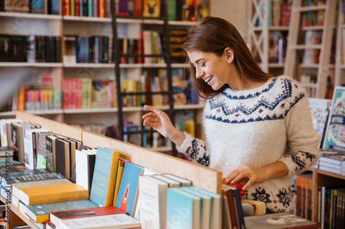 Beautiful brunette woman looking for a book in store photo