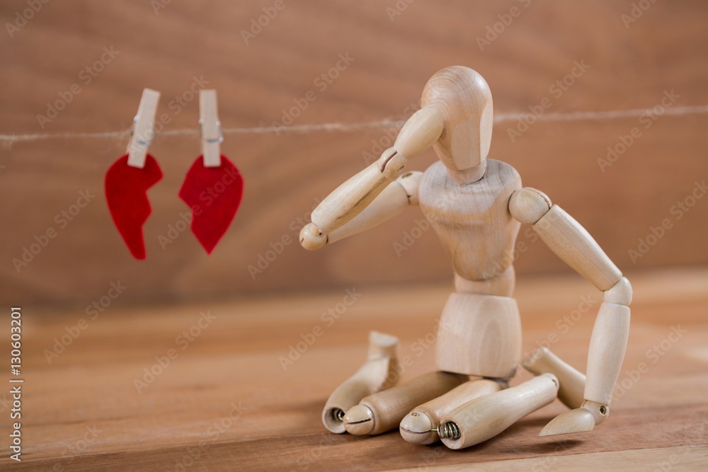 Figurine sitting in front of broken heart Figurine sitting in front of broken heart