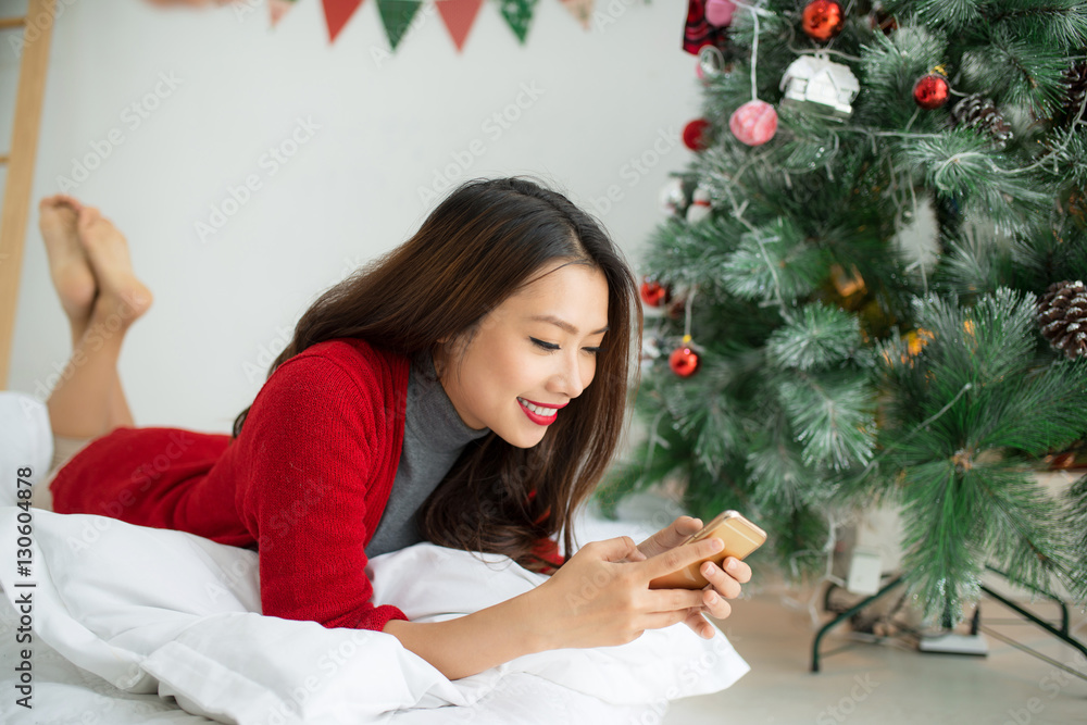 Young smiling asian woman is using mobile phone. Christmas and N Young smiling asian woman is using mobile phone. Christmas and N