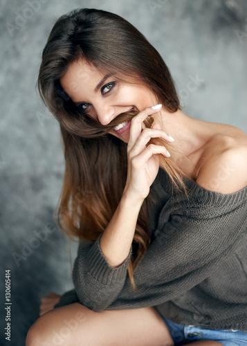 Young and beautiful girl in a sweater smiles and hesitates. Portrait, studio, concept