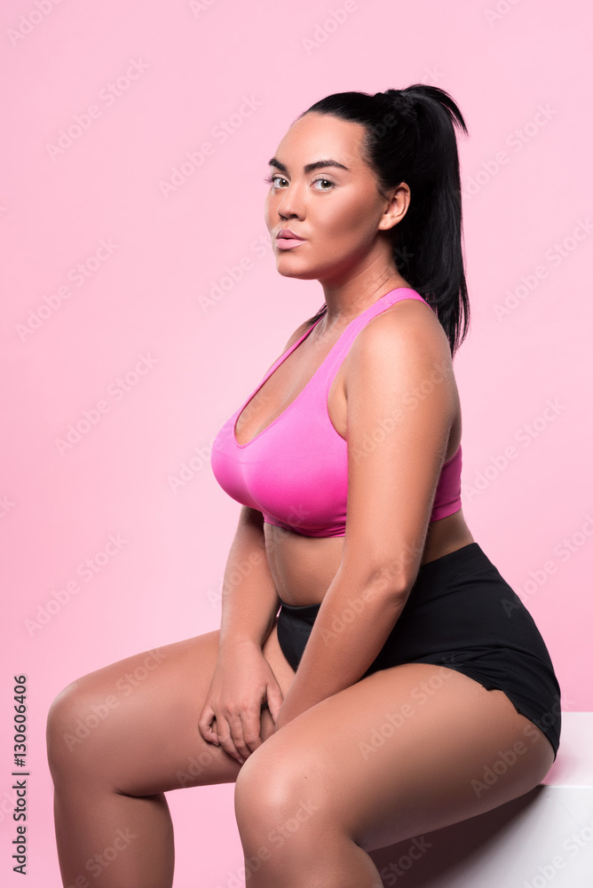 Obraz premium Beautiful plump woman sitting against pink background
