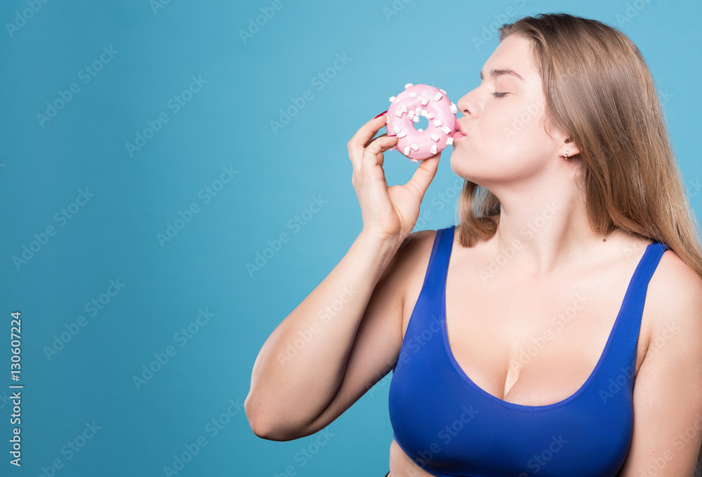 Side view of pretty chubby lady kissing donut Side view of pretty chubby lady kissing donut
