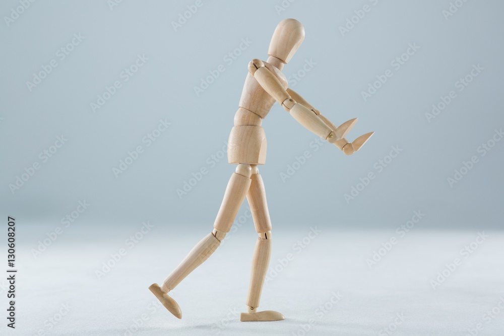 Wooden figurine pretending to push an invisible object Wooden figurine pretending to push an invisible object