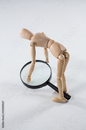 Wooden figurine picking up a magnifying glass