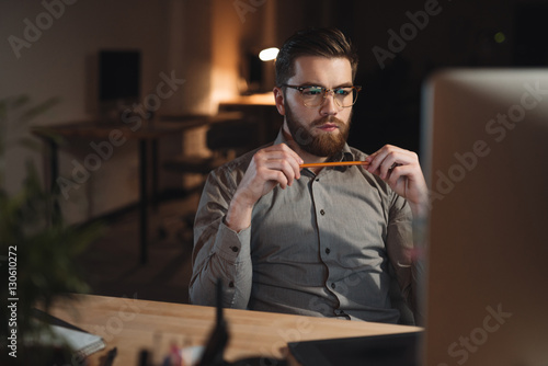 Concentrated bearded web designer working late at night photo