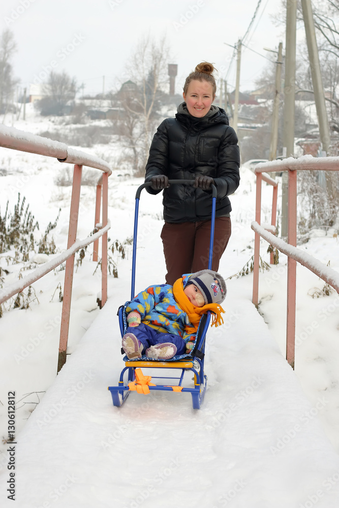 Mother to transfer her child on a sled. The child is tired and going to sleep Stock Photo