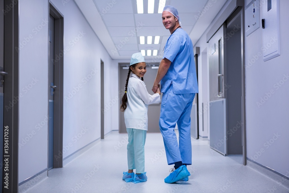 Portrait of doctor and girl walking in corridor