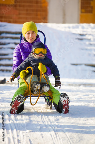 A mom with a child sledding.