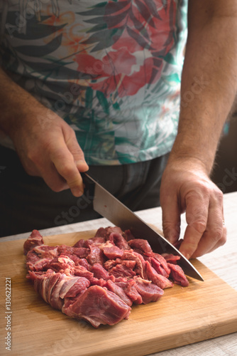 Cutting raw meat on the wooden board vertical