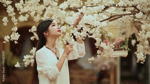 Vietnamese girl with long hair in a white lilac garden photo