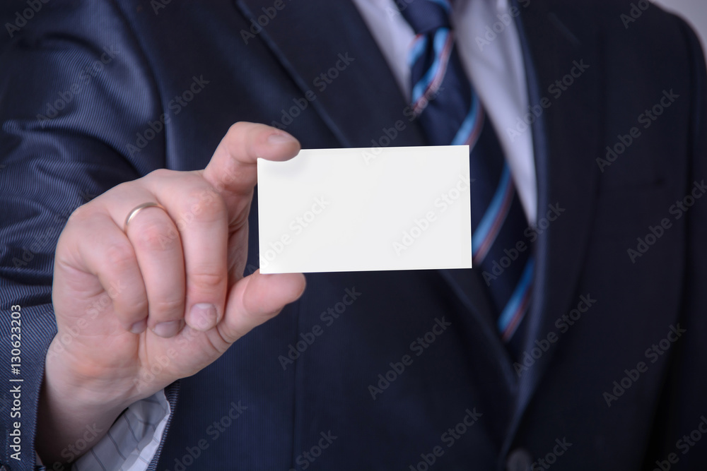 A businessman in a suit showing a business card A businessman in a suit showing a business card