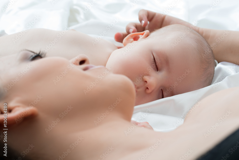 Baby boy sleeping and his mom lying on white linen Baby boy sleeping and his mom lying on white linen