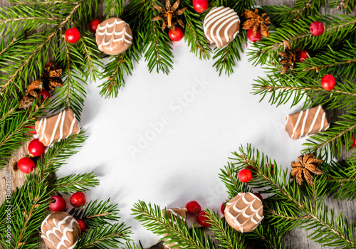 Green Christmas frame with spruce branches, holly and chocolates