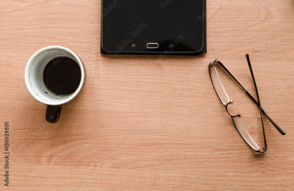 On the table are glasses and a tablet, standing a cup of coffee On the table are glasses and a tablet, standing a cup of coffee