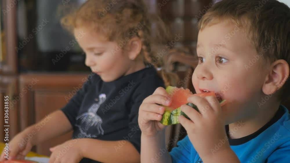 Little boy and girl eat watermelon on kitchen Little boy and girl eat watermelon on kitchen