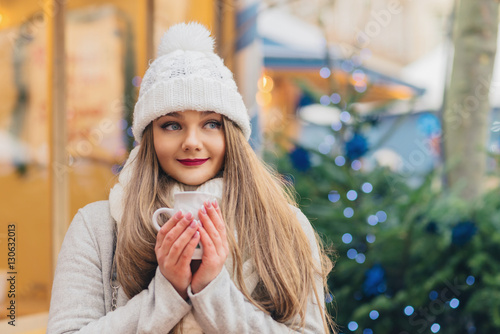 beautiful woman with blue eyes drinks hot wine on christmas mark