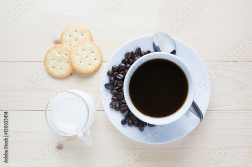 Coffee cup with coffee bean and .cracker on wooden