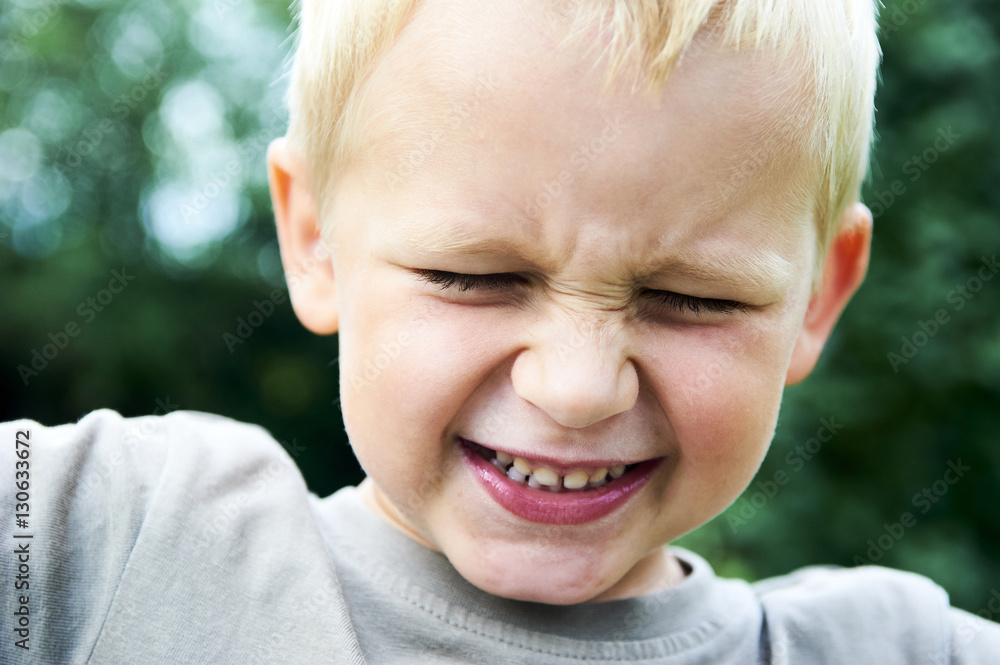Portrait of a little child blond boy making faces. Outside with natural background. Portrait of a little child blond boy making faces. Outside with natural background.