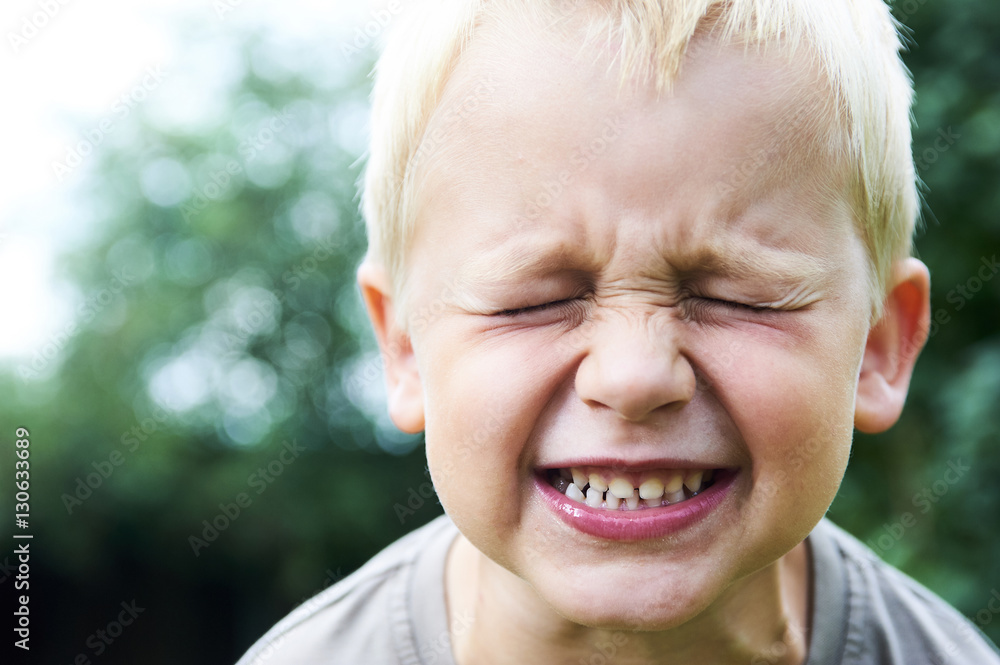Portrait of a little child blond boy making faces. Outside with natural background. Portrait of a little child blond boy making faces. Outside with natural background.
