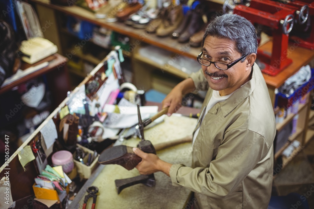 Portrait of smiling shoemaker hammering on a shoe Portrait of smiling shoemaker hammering on a shoe
