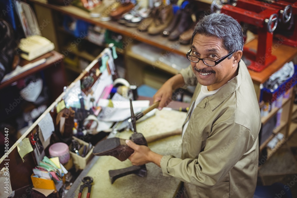 Portrait of smiling shoemaker hammering on a shoe